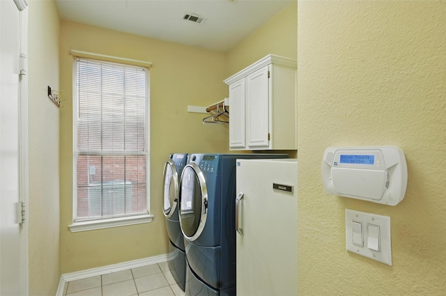 washroom with washing machine and clothes dryer, cabinet space, light tile patterned floors, and plenty of natural light