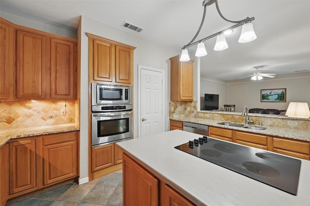kitchen with stainless steel appliances, a sink, decorative backsplash, and brown cabinets