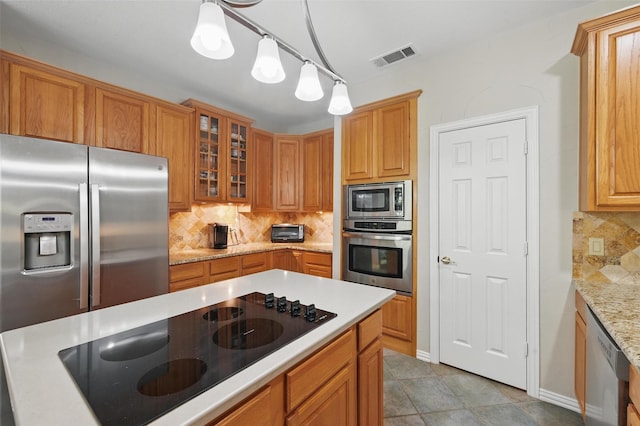 kitchen with stainless steel appliances, decorative backsplash, glass insert cabinets, and decorative light fixtures