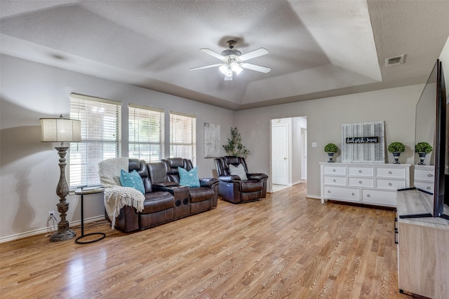 4942 US Highway 69, Denison, TX 75021 - living area featuring a raised ceiling, light wood finished floors, a ceiling fan, baseboards, and a textured ceiling