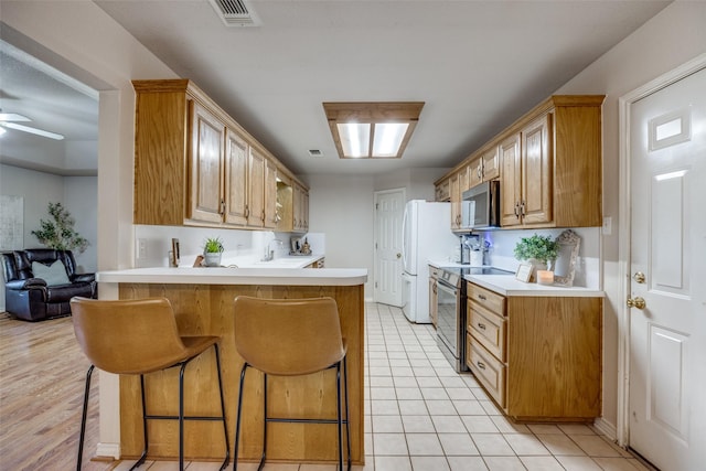 4942 US Highway 69, Denison, TX 75021 - kitchen with appliances with stainless steel finishes, a kitchen bar, light countertops, and a peninsula