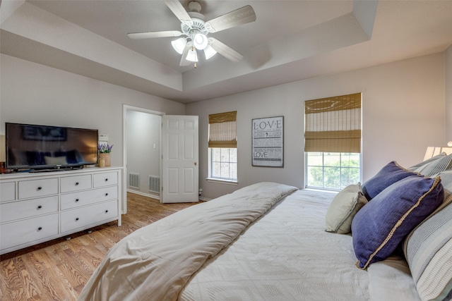 4942 US Highway 69, Denison, TX 75021 - bedroom with light wood-style floors, a tray ceiling, and a ceiling fan