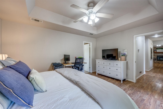 4942 US Highway 69, Denison, TX 75021 - bedroom with a raised ceiling, wood finished floors, baseboards, a glass covered fireplace, and ceiling fan