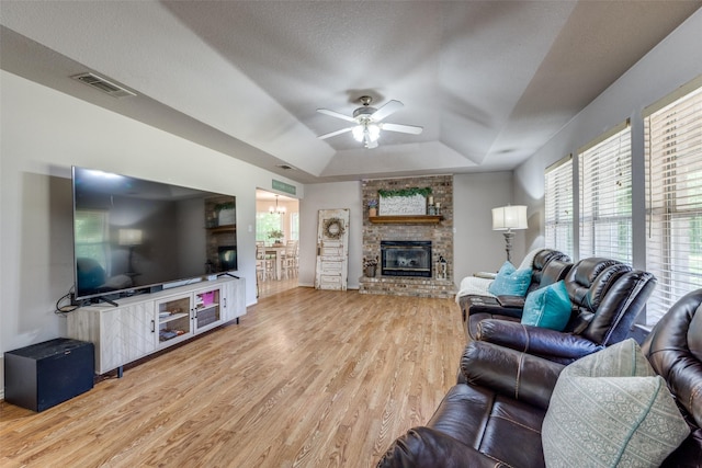4942 US Highway 69, Denison, TX 75021 - living area with a tray ceiling, a fireplace, light wood-type flooring, and ceiling fan