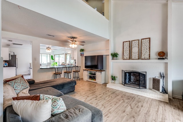 living room with wood finished floors, a fireplace, and ceiling fan