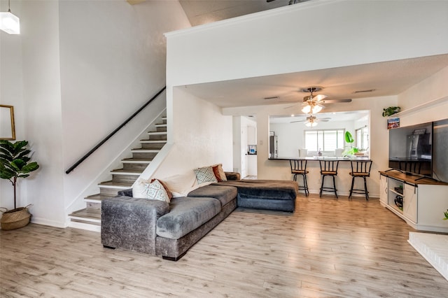 living room featuring wood finished floors, stairs, ceiling fan, and baseboards