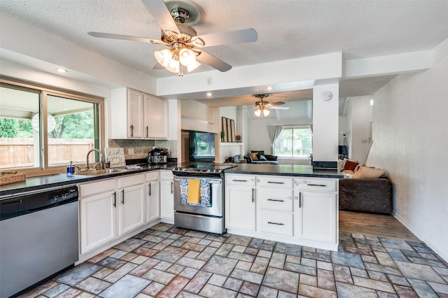 kitchen with stainless steel appliances, a sink, open floor plan, a peninsula, and a ceiling fan