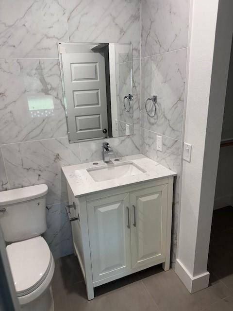 bathroom featuring vanity, toilet, and tile walls