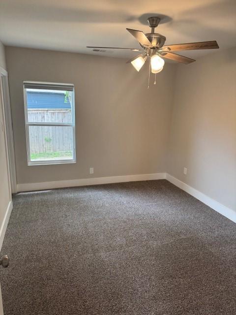 carpeted empty room with baseboards and a ceiling fan