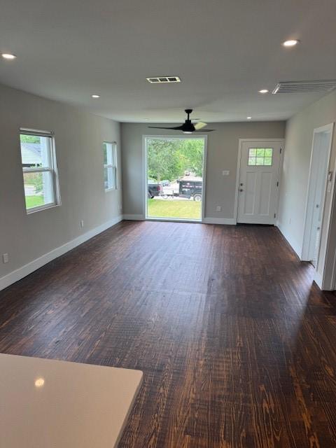 unfurnished living room with dark wood finished floors, a ceiling fan, healthy amount of natural light, baseboards, and recessed lighting