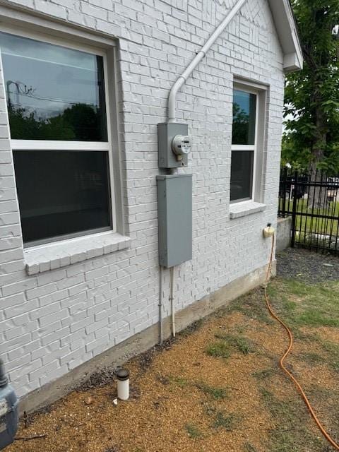 view of side of property featuring brick siding and fence