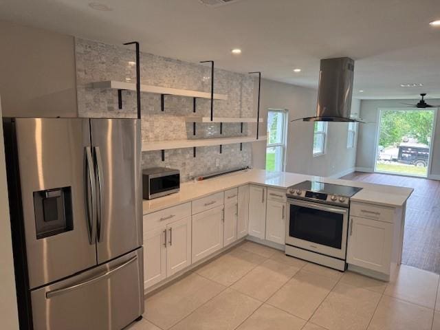 kitchen with appliances with stainless steel finishes, island exhaust hood, open shelves, a peninsula, and light countertops