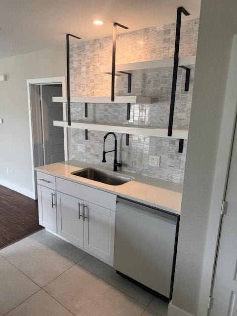 kitchen featuring a sink, dishwasher, backsplash, light countertops, and light tile patterned floors