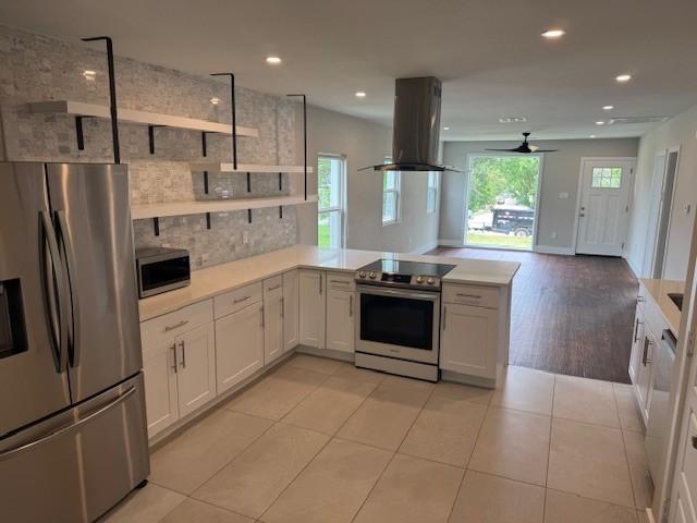 kitchen featuring appliances with stainless steel finishes, island exhaust hood, open shelves, a peninsula, and recessed lighting