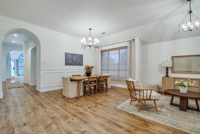 6520 Creek Crossing Ln, Sachse, TX 75048 - dining room featuring a chandelier, light wood finished floors, arched walkways, and wainscoting