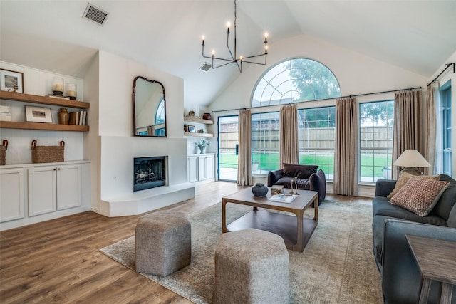 6520 Creek Crossing Ln, Sachse, TX 75048 - living room featuring a chandelier, wood finished floors, a fireplace with raised hearth, and high vaulted ceiling