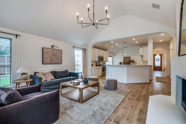 6520 Creek Crossing Ln, Sachse, TX 75048 - living area with arched walkways, a chandelier, light wood-style floors, high vaulted ceiling, and recessed lighting