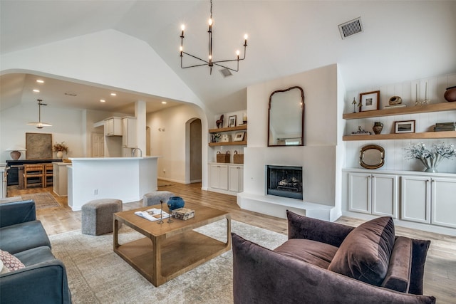 6520 Creek Crossing Ln, Sachse, TX 75048 - living area with arched walkways, a chandelier, high vaulted ceiling, light wood finished floors, and a fireplace with raised hearth