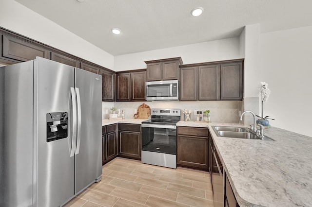 2867 Baneberry Ln, Mesquite, TX 75150 - kitchen with appliances with stainless steel finishes, a sink, dark brown cabinetry, tasteful backsplash, and light countertops