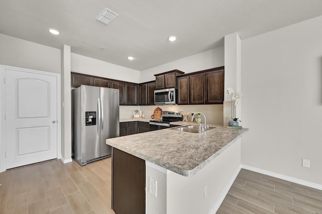 2867 Baneberry Ln, Mesquite, TX 75150 - kitchen with appliances with stainless steel finishes, a sink, dark brown cabinetry, light countertops, and baseboards