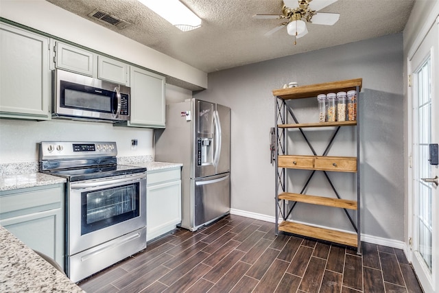 2802 Rio Grande Pass, Mesquite, TX 75150 - kitchen featuring appliances with stainless steel finishes, dark wood-type flooring, baseboards, a textured ceiling, and ceiling fan