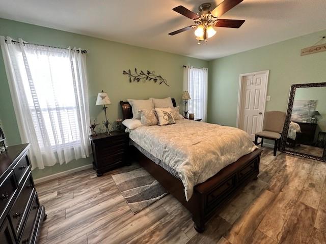 bedroom with multiple windows, light wood-style flooring, and ceiling fan