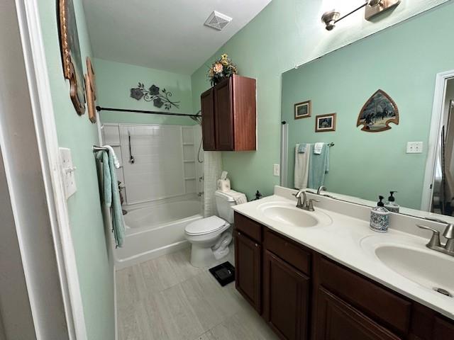 full bath featuring toilet, double vanity, and tub / shower combination