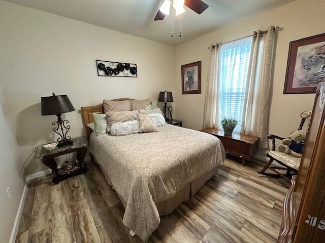 bedroom with wood finished floors, baseboards, and ceiling fan
