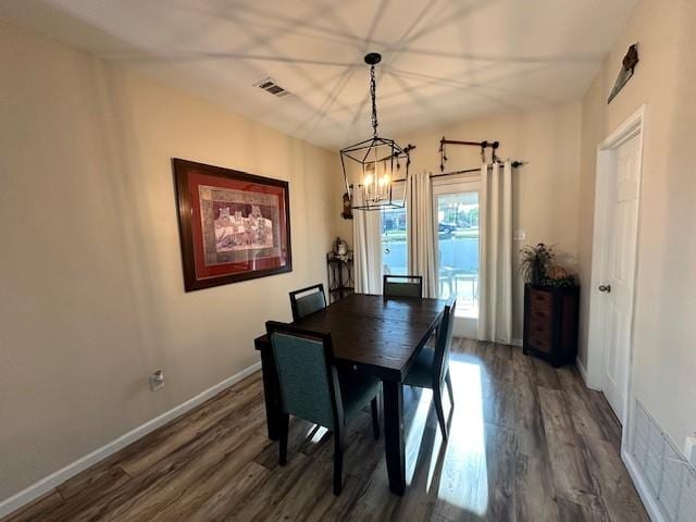 dining space featuring a chandelier, dark wood finished floors, and baseboards