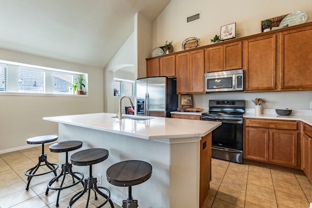 1100 Thicket Dr, Mansfield, TX 76063 - kitchen featuring stainless steel appliances, a sink, brown cabinetry, a kitchen breakfast bar, and high vaulted ceiling