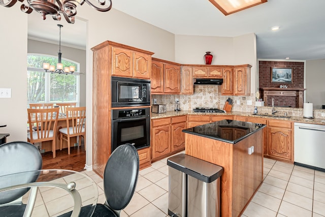 kitchen with black appliances, a sink, a chandelier, under cabinet range hood, and decorative backsplash
