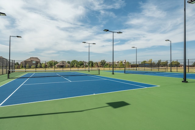 view of tennis court featuring community basketball court and fence