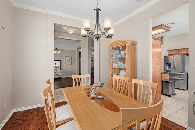 dining area with crown molding, a chandelier, light wood-style floors, and baseboards