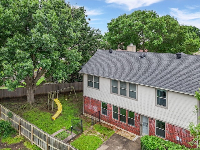 3516 Napolean Ct, Plano, TX 75023 - view of side of property featuring roof with shingles, brick siding, a playground, a fenced backyard, and a chimney