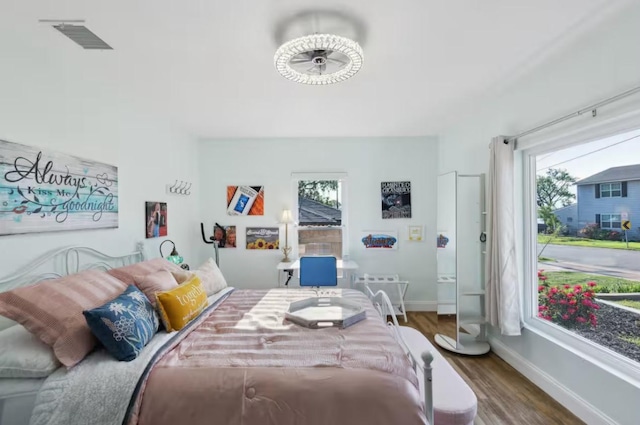 bedroom with multiple windows, wood finished floors, and baseboards