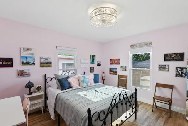 bedroom with multiple windows, wood finished floors, and baseboards