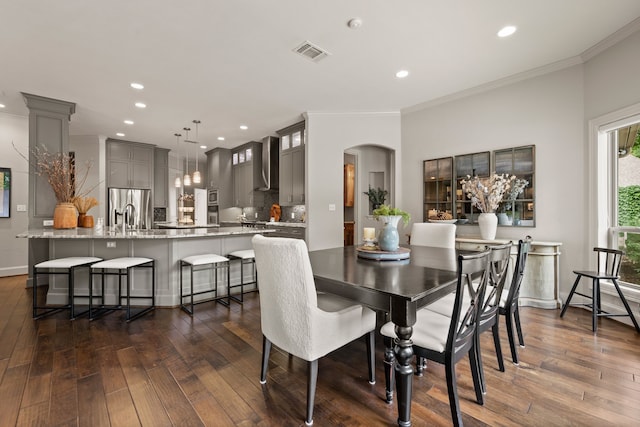 dining space with arched walkways, ornamental molding, dark wood-style flooring, recessed lighting, and baseboards