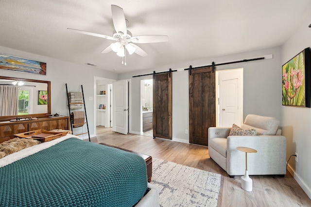 bedroom with a barn door, light wood finished floors, baseboards, and a ceiling fan