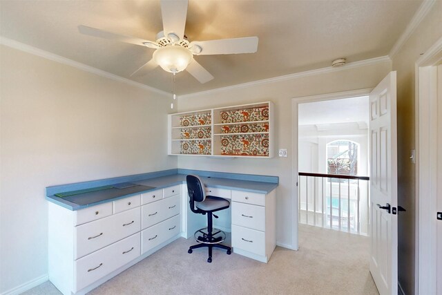 office area with built in desk, light colored carpet, a ceiling fan, ornamental molding, and baseboards
