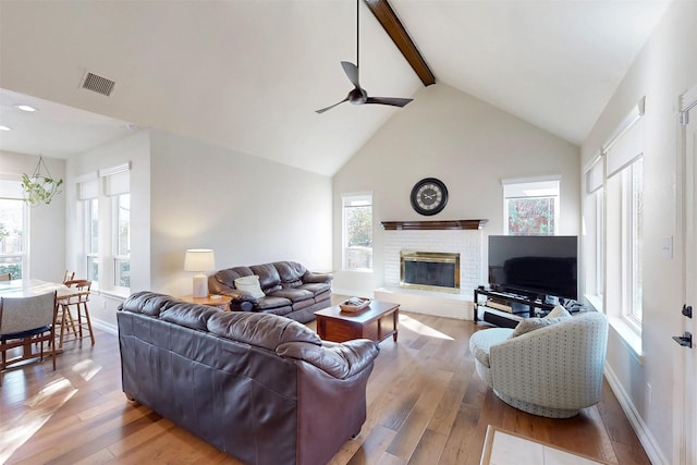 living area featuring beamed ceiling, hardwood / wood-style flooring, ceiling fan, a brick fireplace, and recessed lighting