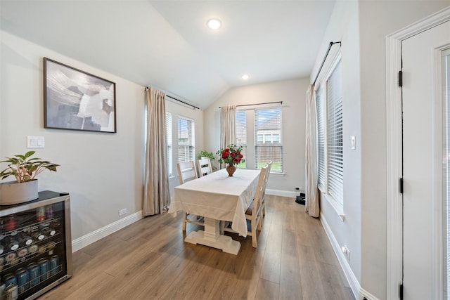 dining room featuring beverage cooler, light wood-type flooring, baseboards, vaulted ceiling, and recessed lighting