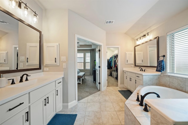 full bath with a garden tub, baseboards, and two vanities
