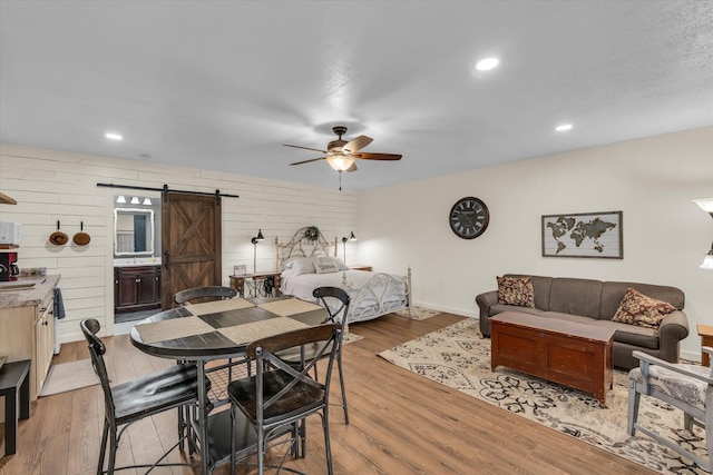 3601 Orchard Ln, Waco, TX 76705 - dining area featuring a barn door, ceiling fan, light wood finished floors, and baseboards