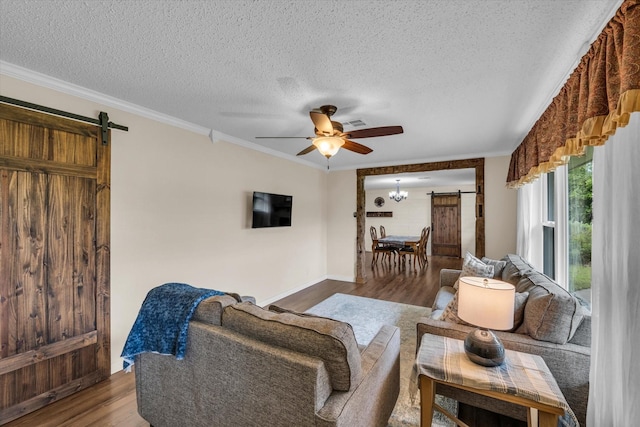 3601 Orchard Ln, Waco, TX 76705 - living area featuring a barn door, wood finished floors, a textured ceiling, ceiling fan, and crown molding