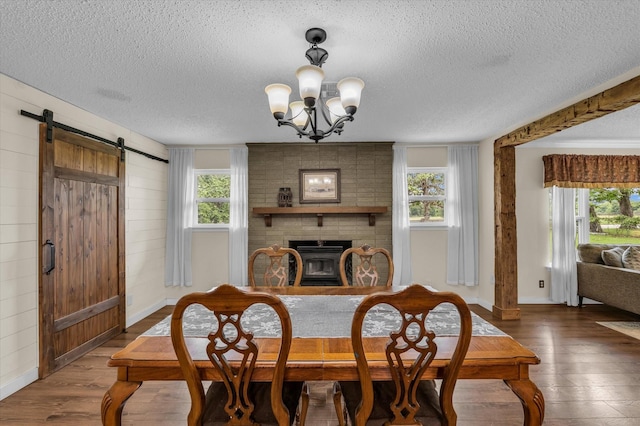 3601 Orchard Ln, Waco, TX 76705 - dining room featuring a textured ceiling, wood finished floors, a chandelier, baseboards, and a fireplace