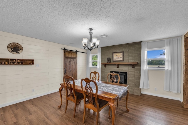 3601 Orchard Ln, Waco, TX 76705 - dining room with a barn door, wood finished floors, a chandelier, a textured ceiling, and baseboards
