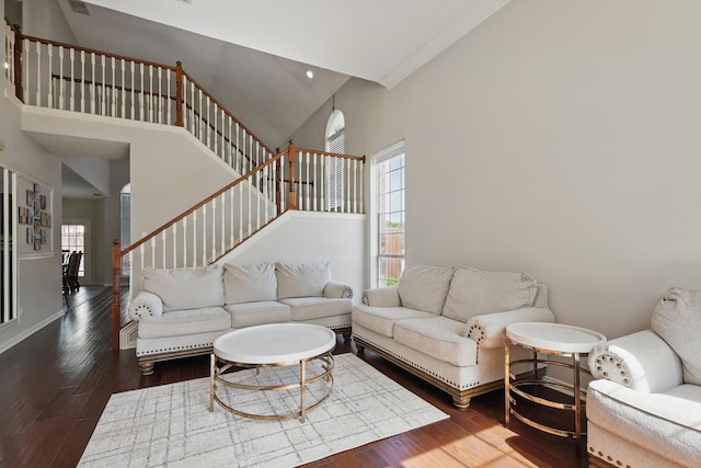 living room featuring plenty of natural light, crown molding, wood finished floors, stairway, and a high ceiling