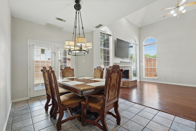 tiled dining area featuring a chandelier, baseboards, a fireplace, and ceiling fan