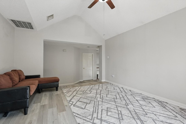 living room with ceiling fan, lofted ceiling, light wood-type flooring, and baseboards