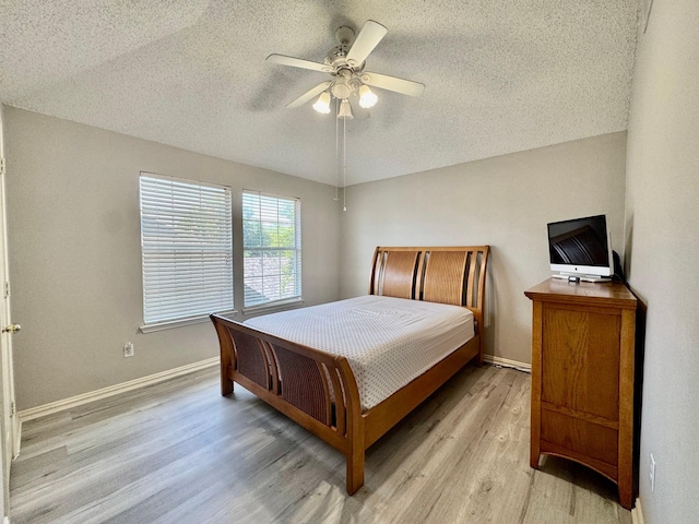 bedroom with a textured ceiling, light wood-style flooring, baseboards, and a ceiling fan